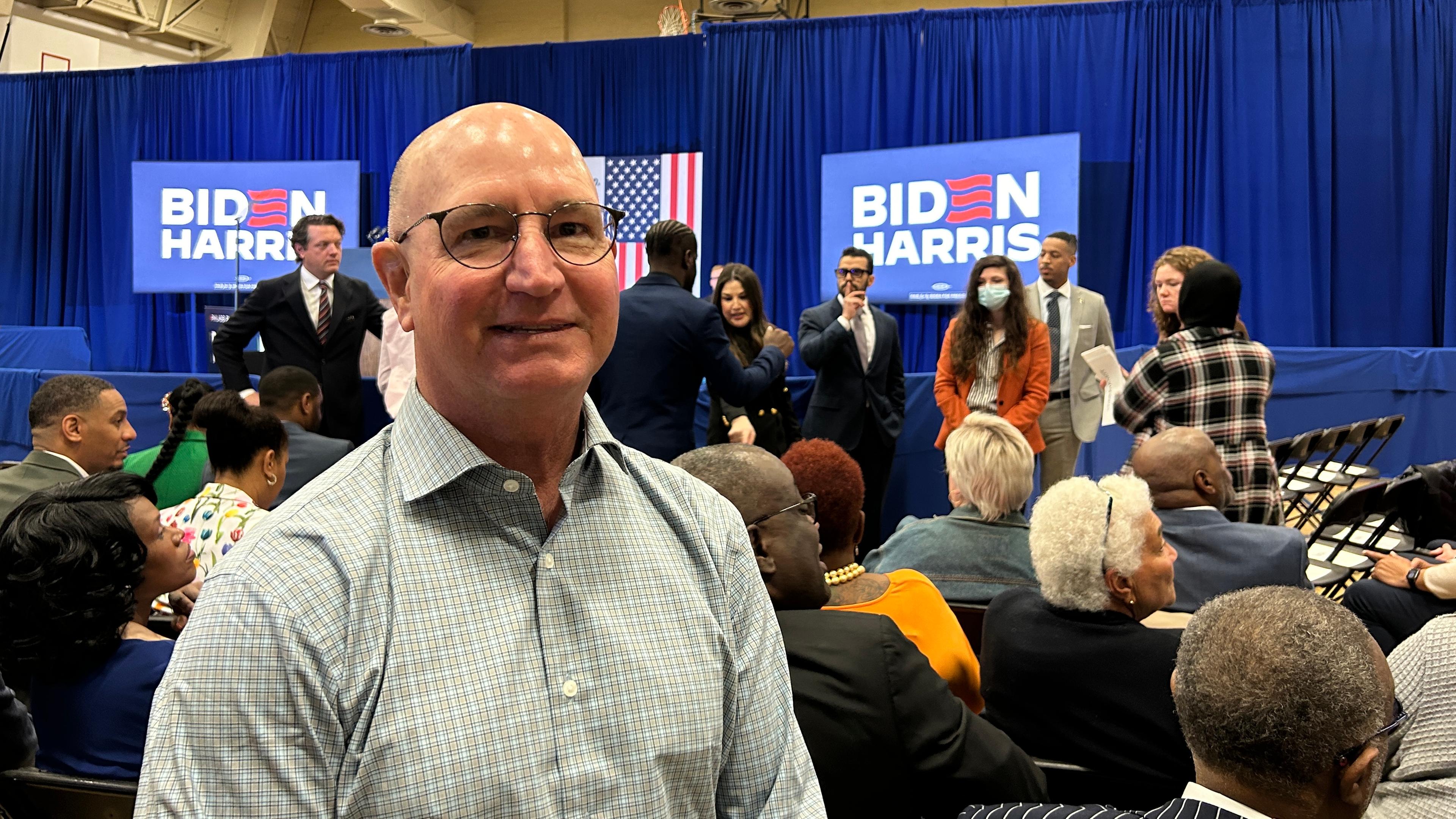 Ein Mann mit Glatze und Hemd steht im Zuschauerraum einer Wahlkampfveranstaltung von US-Präsident Joe Biden.