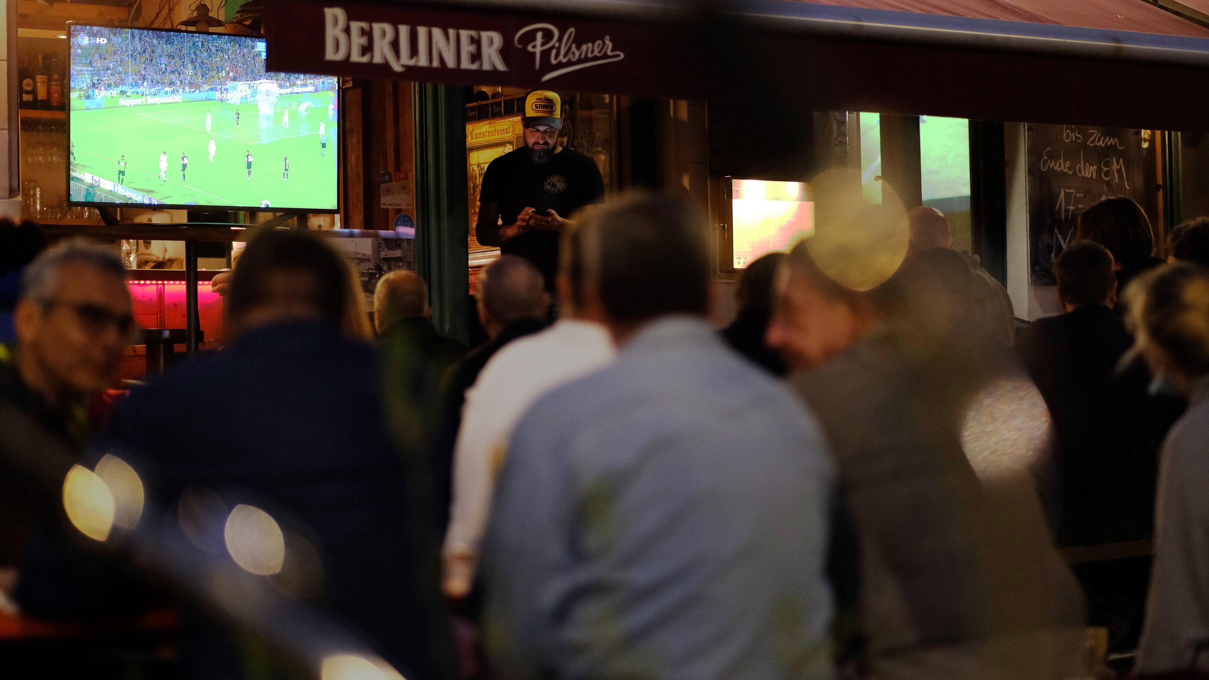Fußballfans verfolgen das Spiel Deutschland - Ungarn bei der Fußball-Europmeisterschaft 2020 vor einer Bar im Berliner Stadtteil Pankow.