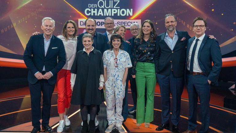 "Der Quiz-Champion - Das Doppel-Special": Johannes B. Kerner, Katrin Müller-Hohenstein, Katharina Thalbach, Johann Lafer, Frank Plasberg, Anna Thalbach, Anne Gesthuysen, Marcel Reif, Sarah Wiener, Kurt Krömer, Michael "Bully" Herbig stehen im Studio vor dem Sendungslogo und lachen in die Kamera.
