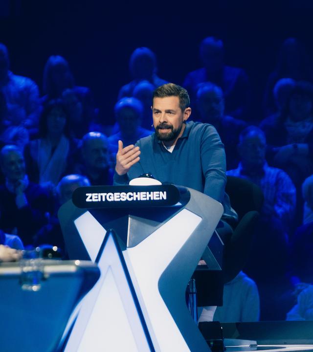 "Der Quiz-Champion": Klaas Heufer-Umlauf sitzt am Ratepult im Studio und gestikuliert.