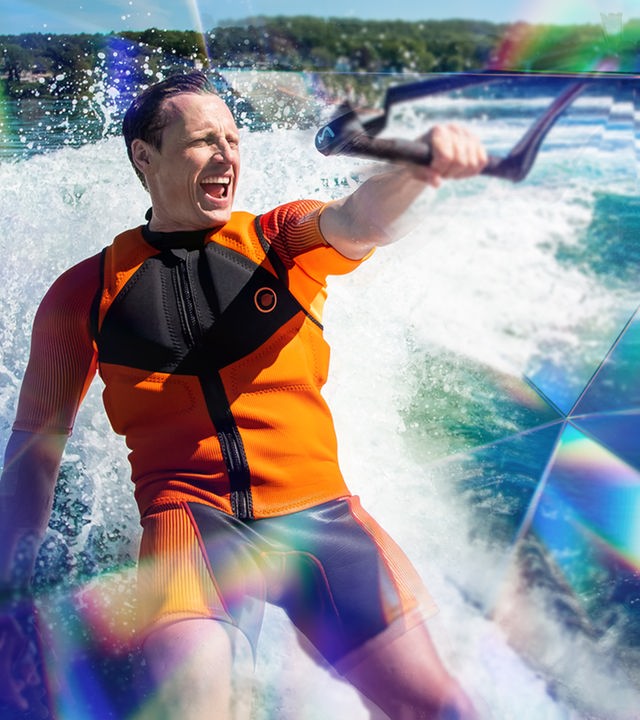 Schauspieler Patrick Kalupa fährt bei Dreharbeiten Wasserski und hält sich mit nur einer Hand fest.