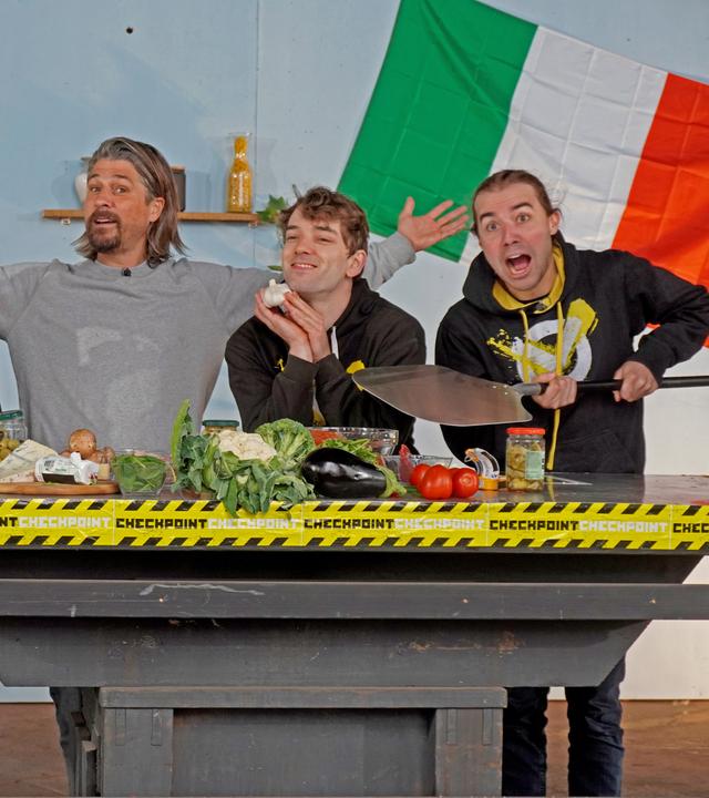 Checkpoint: Das Testteam und Tommy Scheel stehen hinter einem Tisch, auf dem allerlei Zutaten fürs Pizzabacken bereit liegen. 