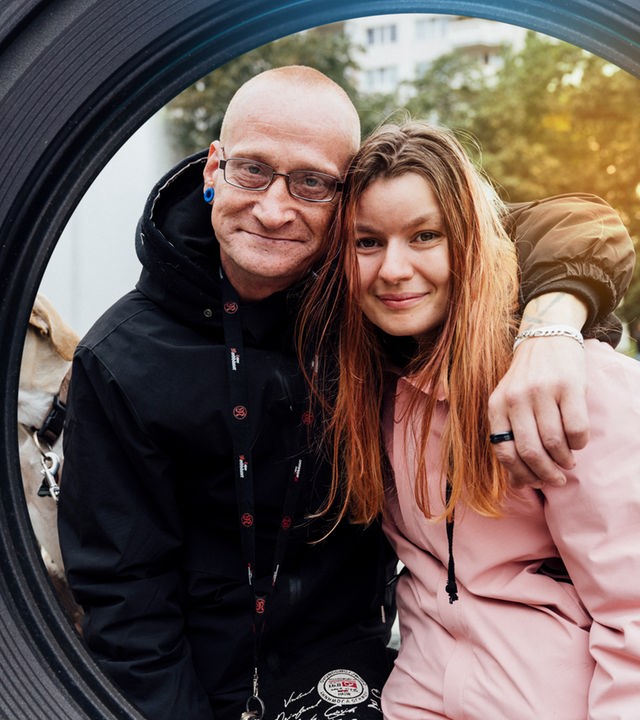 Vor einem Springbrunnen: Ein Mann, "Monte", hat den Arm um die Schulter seiner Freundin gelegt. Neben ihnen sitzt ein Hund.