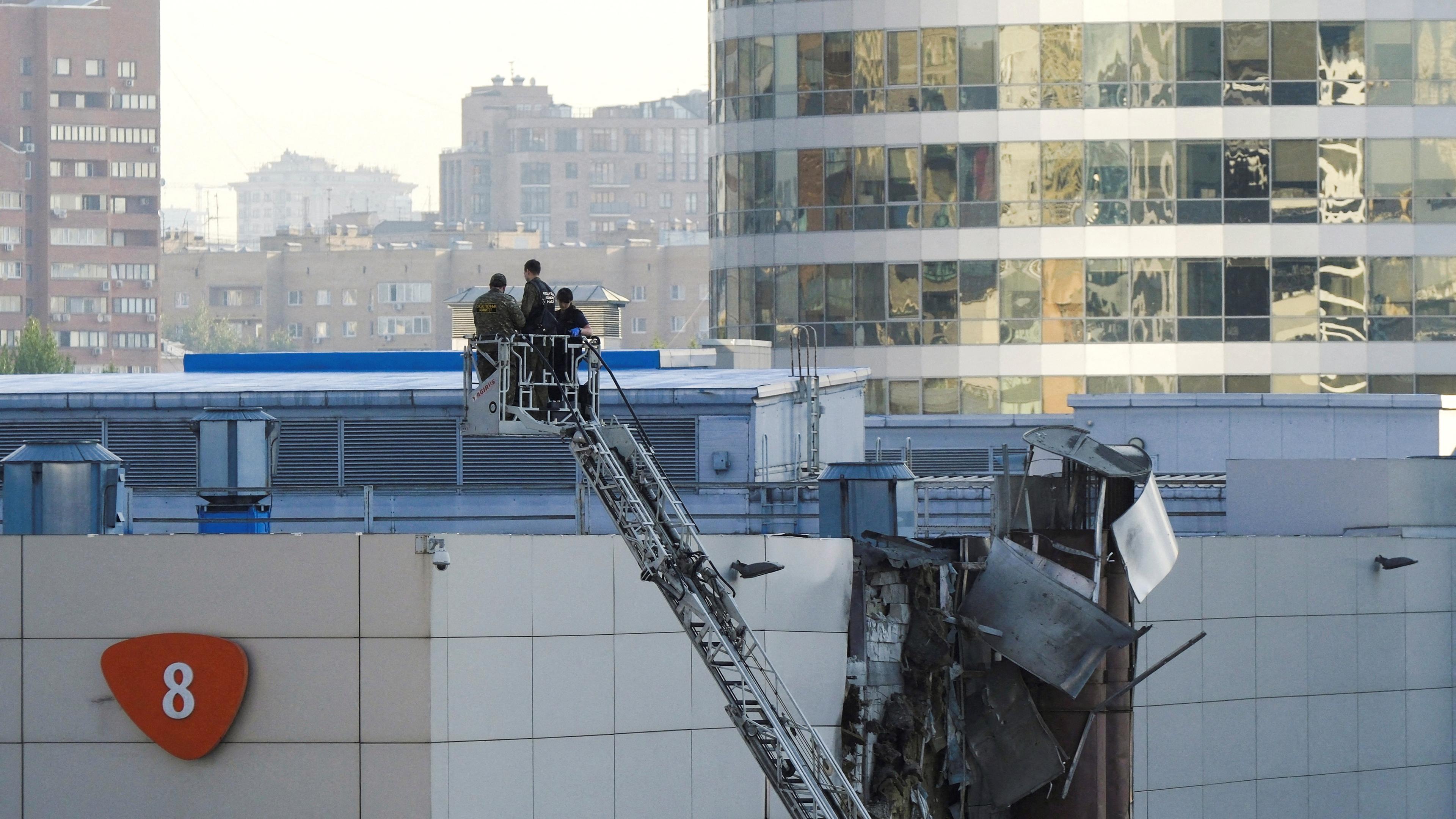 Ermittler arbeiten in der Nähe eines beschädigten Daches, nachdem am 18. 08. 2023 in Moskau, Russland, eine ukrainische Drohne abgeschossen wurde. 