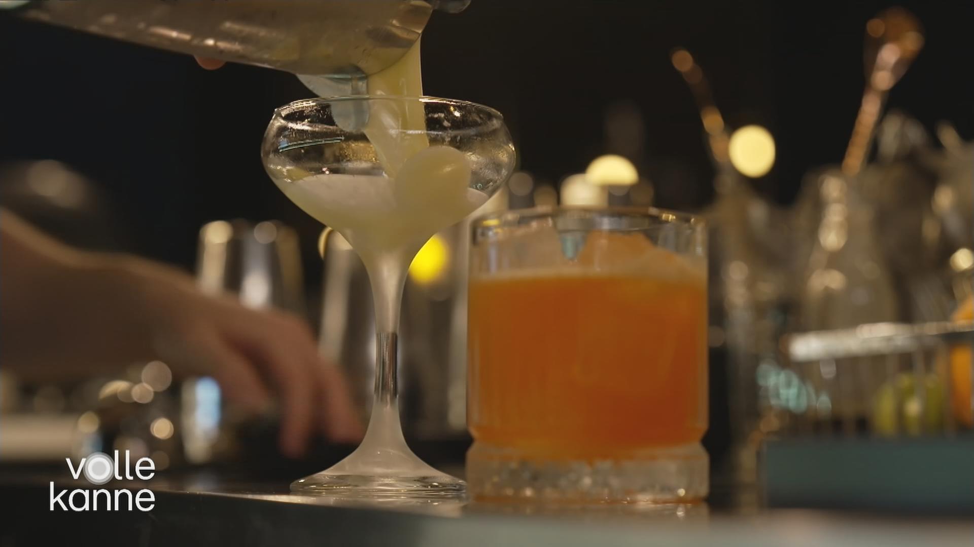 Zwei Cocktailgläser auf dem Tisch: In ein Glas wird noch ein Cocktail gefüllt