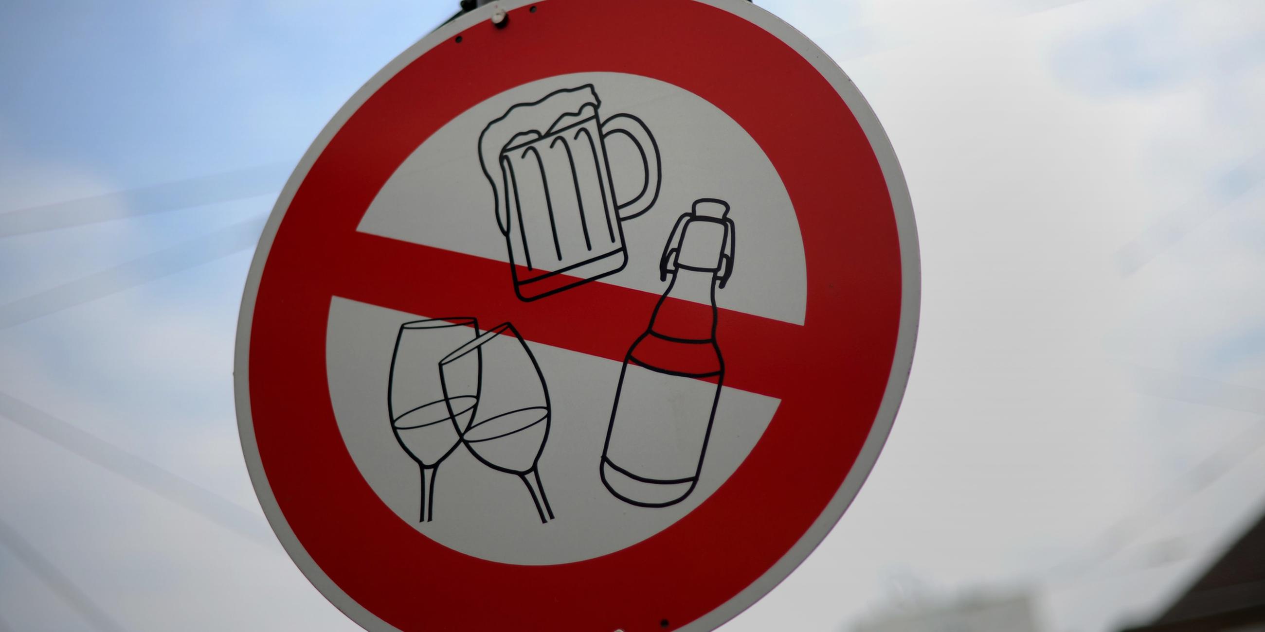Auf einem Verkehrsschild sind Symbole für alkoholische Getränke wie Bier und Wein durchgestrichen.