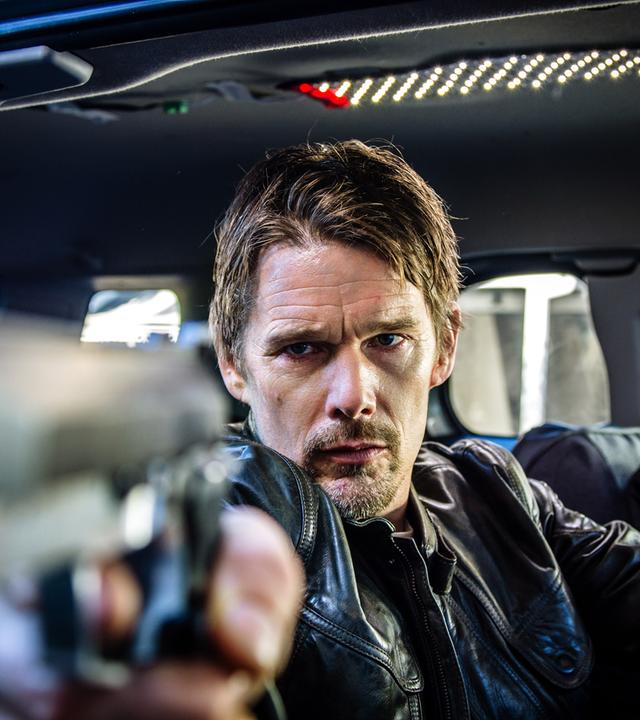 Travis Conrad (Ethan Hawke) sitzt in einem Auto und zielt mit einer Pistole aus dem Seitenfenster.