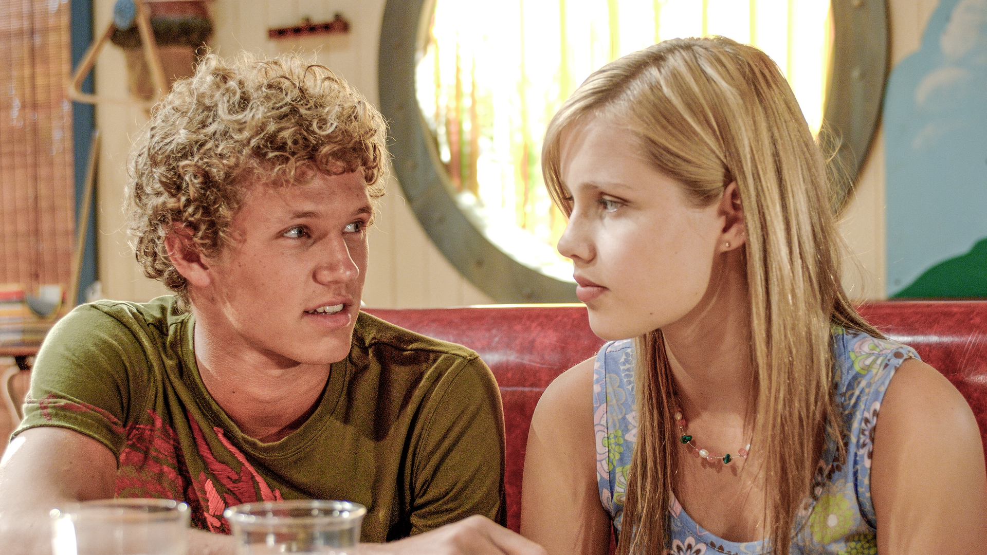 Emma (rechts) und Byron (links) sitzen in der Bar und kommen sich näher. 