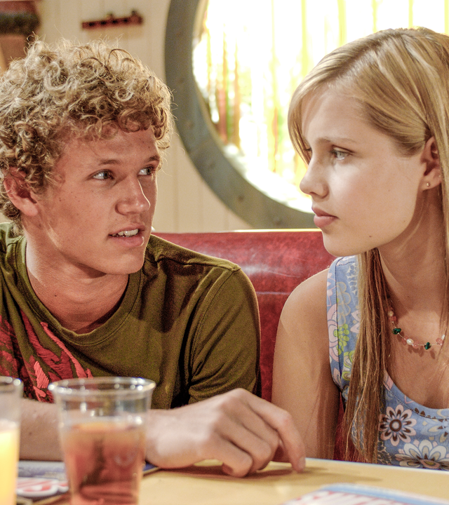 Emma (rechts) und Byron (links) sitzen in der Bar und kommen sich näher. 