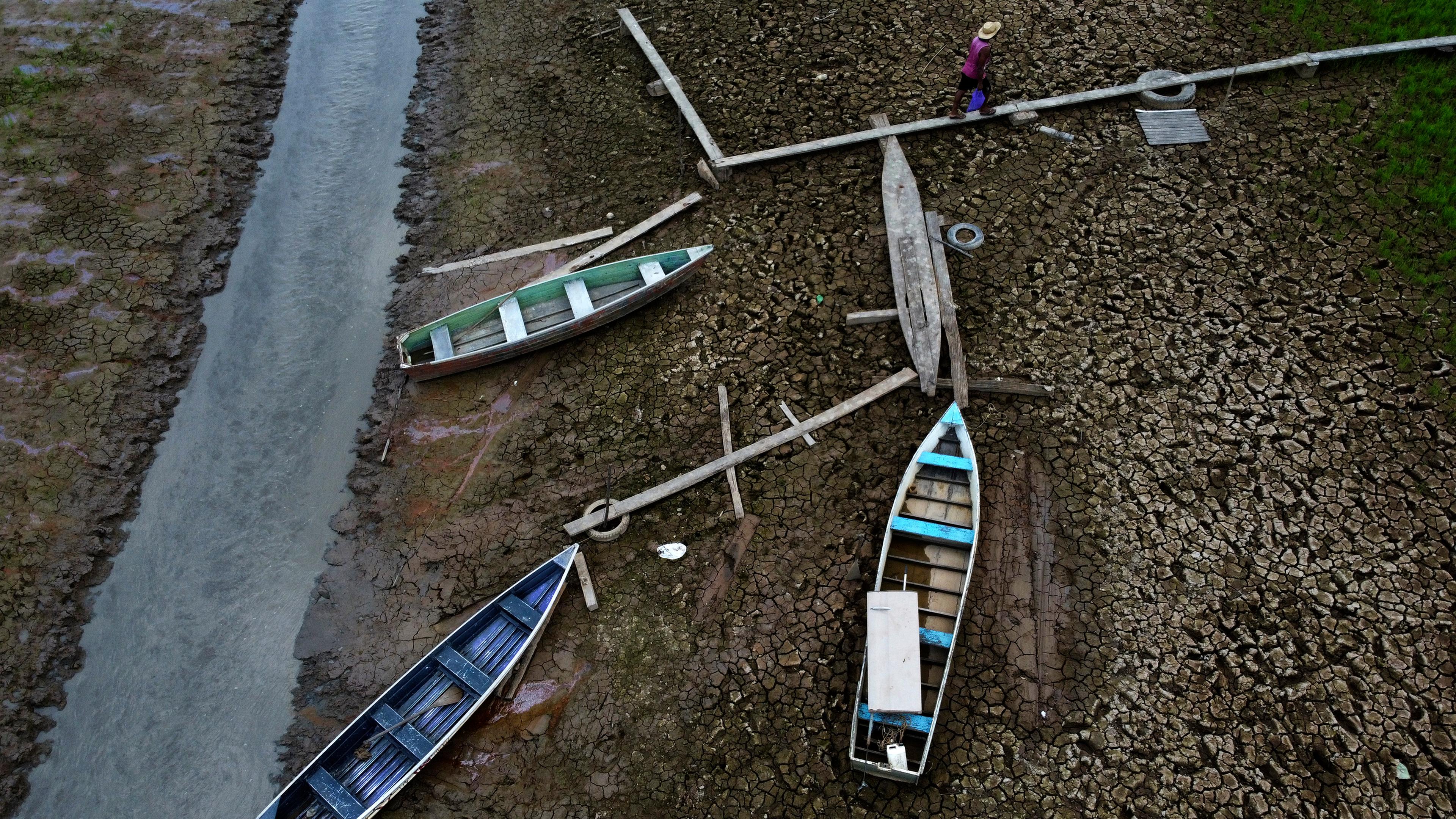 Ein Anwohner geht neben Booten auf einem trockenen Abschnitt des Solimoes-Flusses in einer ländlichen Gegend des Staates Amazonas. 