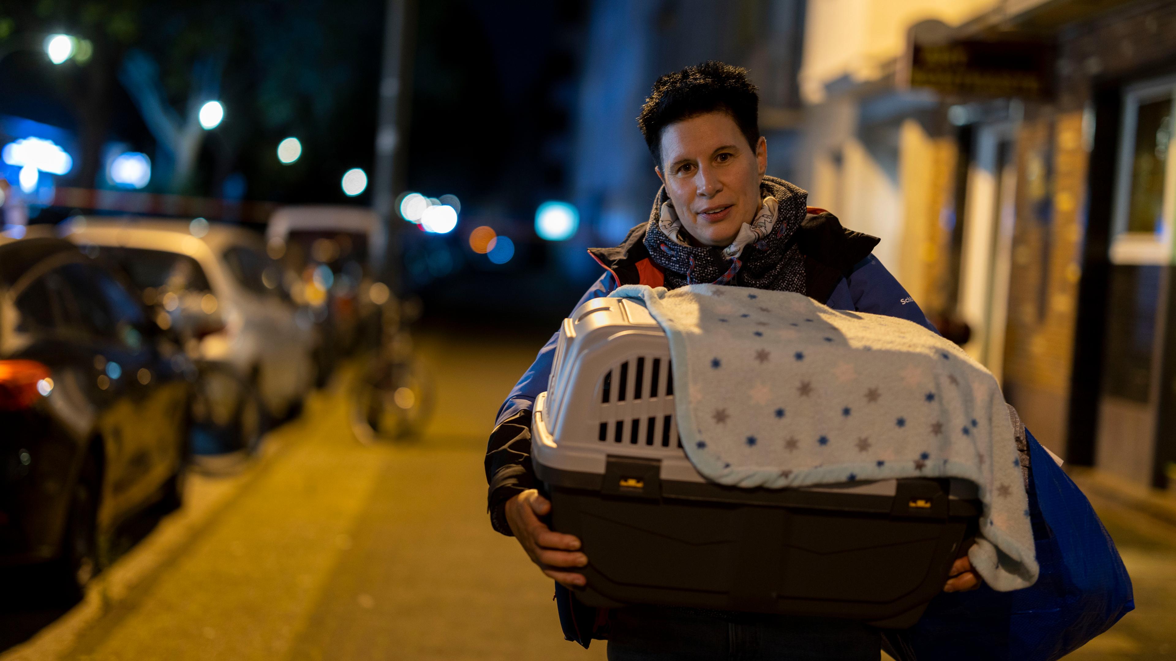 Frau trägt ihre Katze, während sie ihre Wohnung wegen einer zu entschärfenden Fliegerbombe verlässt.