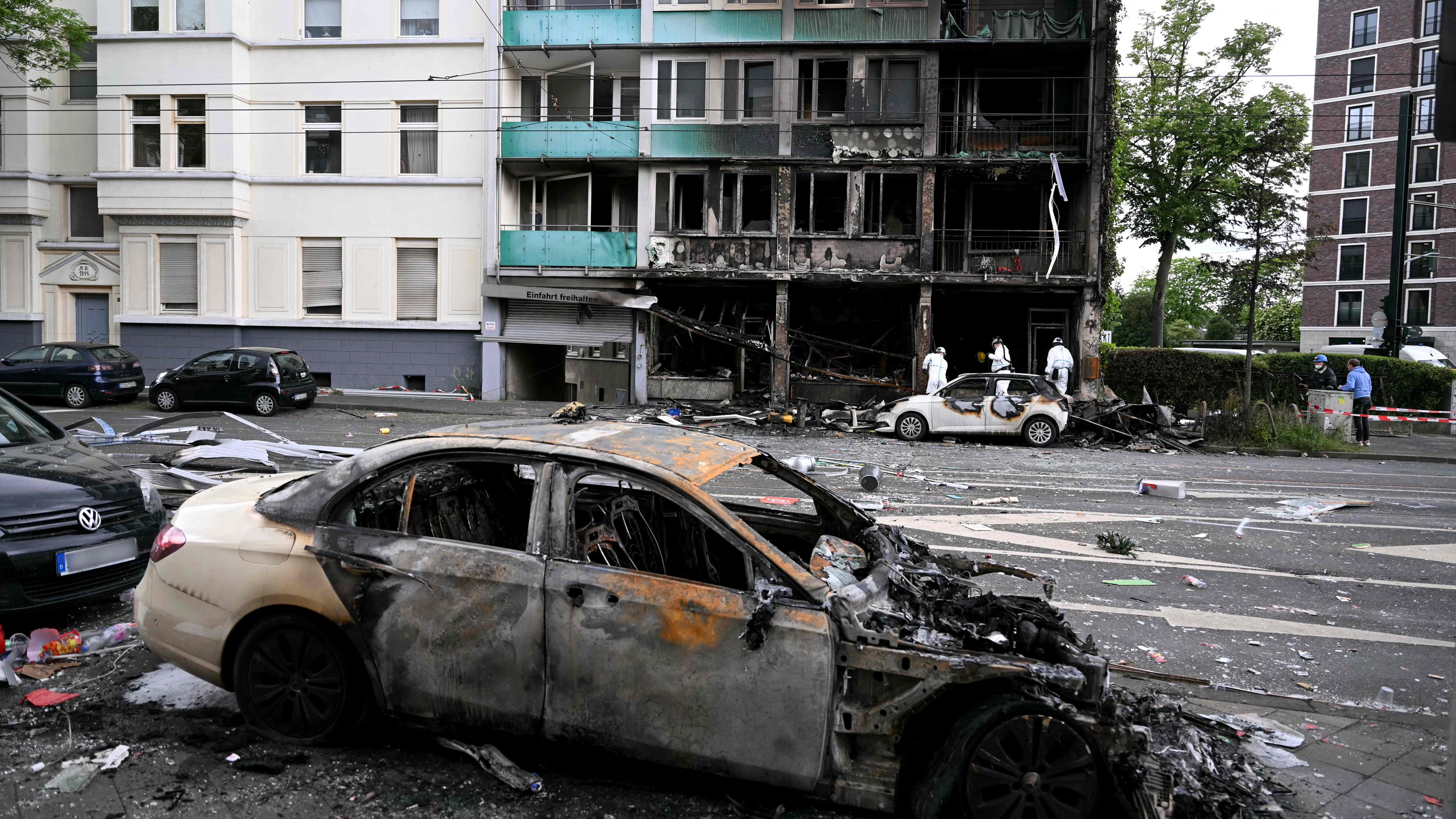 Beschädigte Autos sind vor den Ruinen eines Gebäudes zu sehen, das am 16. Mai 2024 in Düsseldorf durch einen Brand zerstört wurde