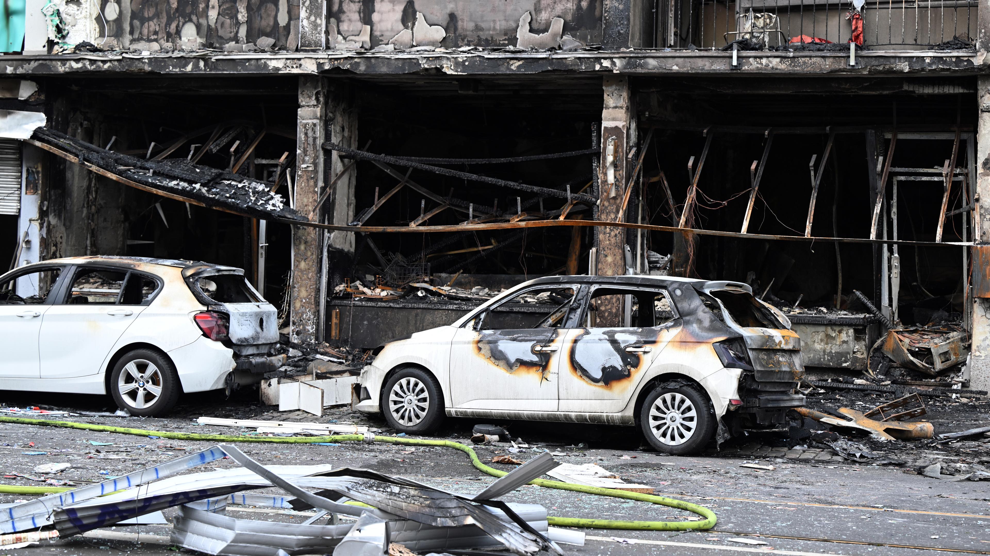 Nordrhein-Westfalen, Düsseldorf: Ausgebrannte Autos stehen vor einem Wohnhaus, in dem ein Brand wütete.