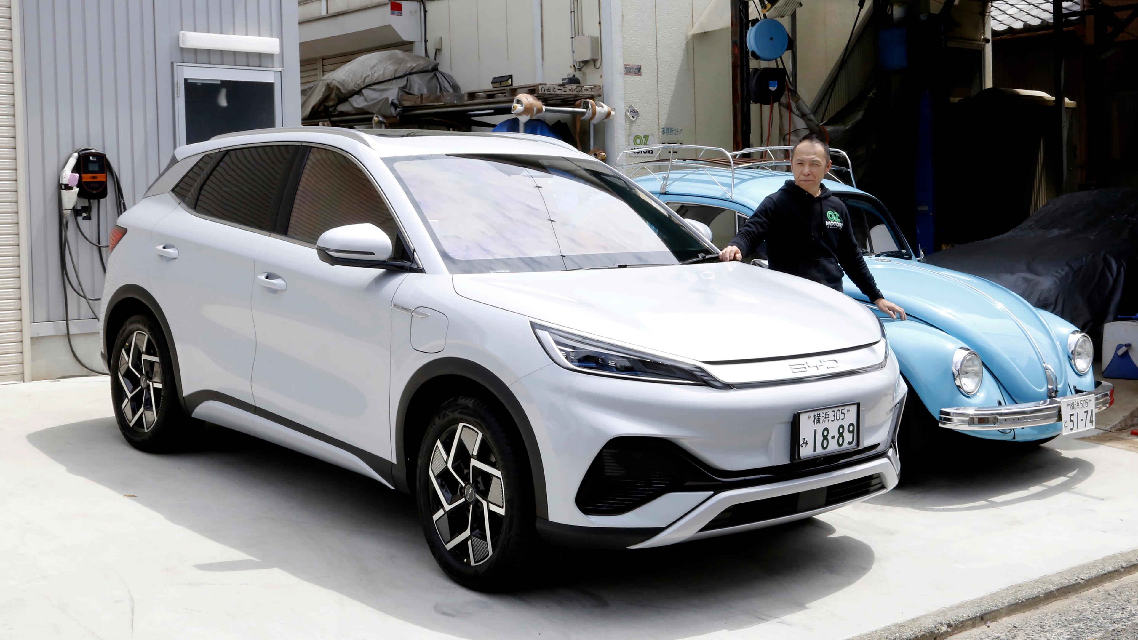 Osamu Furukawa steht am Dienstag, 25. April 2023, in Yokohama, südlich von Tokio, neben seinem neuen Elektroauto BYD ATTO 3, das neben einem zum Elektroauto umgebauten Volkswagen geparkt ist.