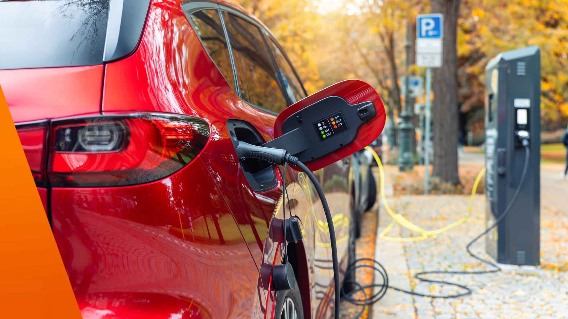 Ein Elektroauto steht am Straßenrand und wird über eine öffentliche Ladesäule geladen. Mehrere Kabel liegen am Boden, während im Hintergrund weitere Ladepunkte und parkende Autos zu sehen sind. Das Bild macht sichtbar, dass ohne eigene Wallbox viele Mieter auf öffentliche Lademöglichkeiten angewiesen sind.
