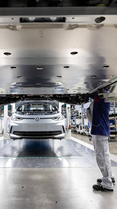 Mitarbeiter arbeiten am Unterboden mit der Batterie eines Elektrofahrzeugs von VW