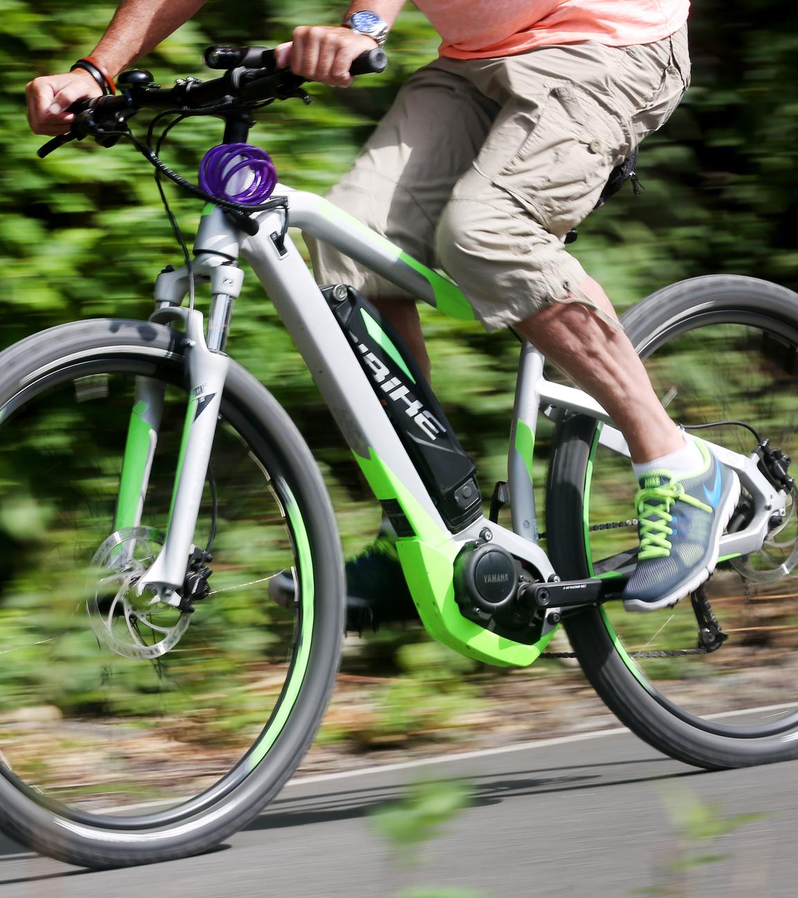 Radfahrer ist mit E-Mountainbike auf Radweg schnell unterwegs.
