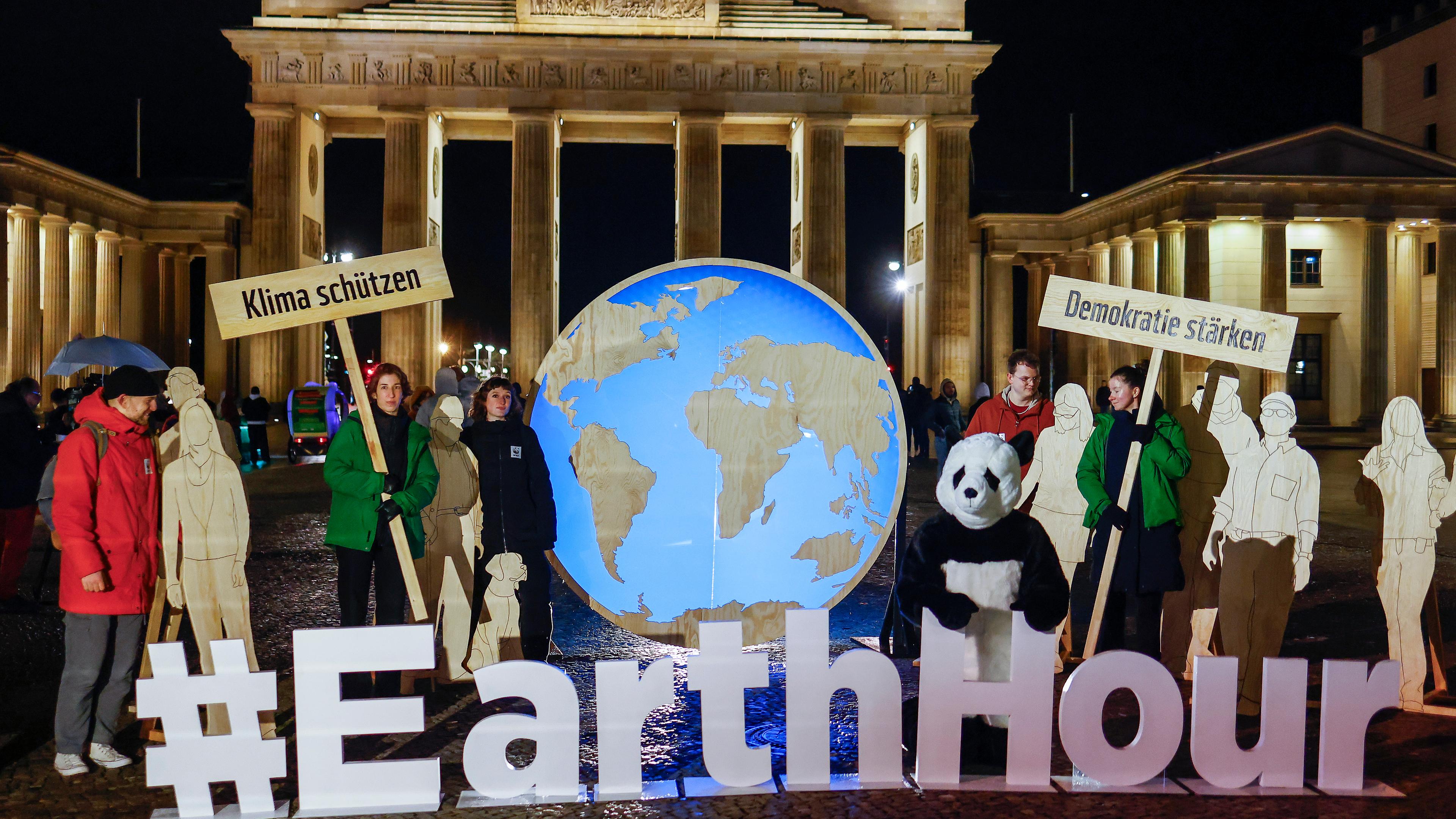 Aktivisten stehen während der "Earth Hour" vor dem Brandenburger Tor in Berlin