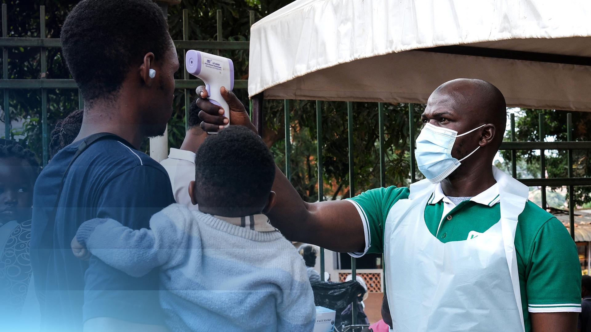 Ein Gesundheitsbeamter untersucht Menschen mit einem Fieberthermometer in Kampala, Uganda.