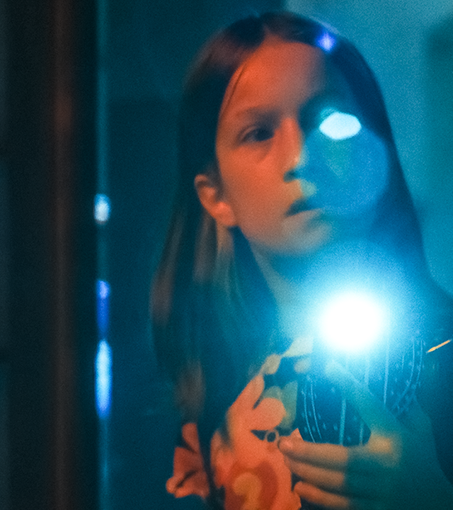 Liv leuchtet im Keller der Schule mit einer Taschenlampe, deren Schein blendet.