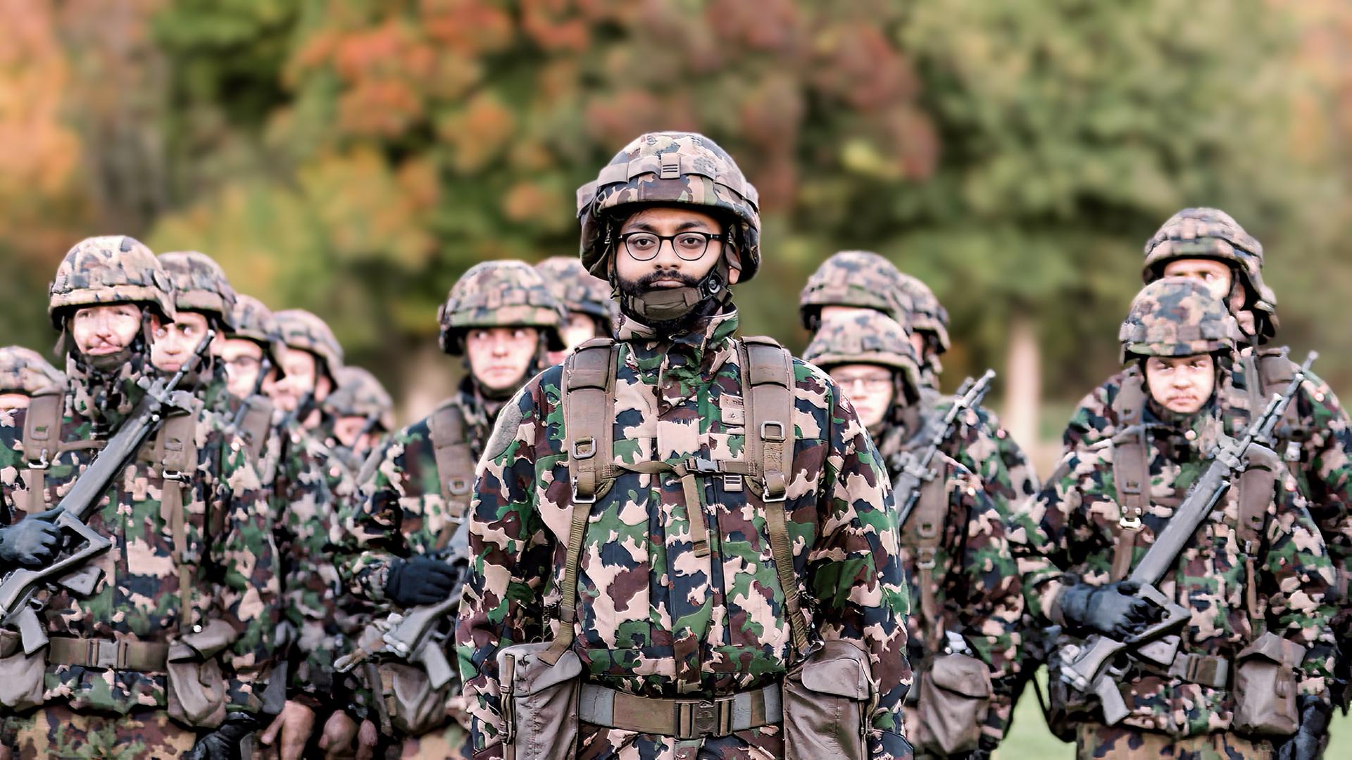 Eine Gruppe von Soldaten in Tarnuniform steht in Formation im Freien, im Vordergrund ein Soldat mit Brille und Bart.