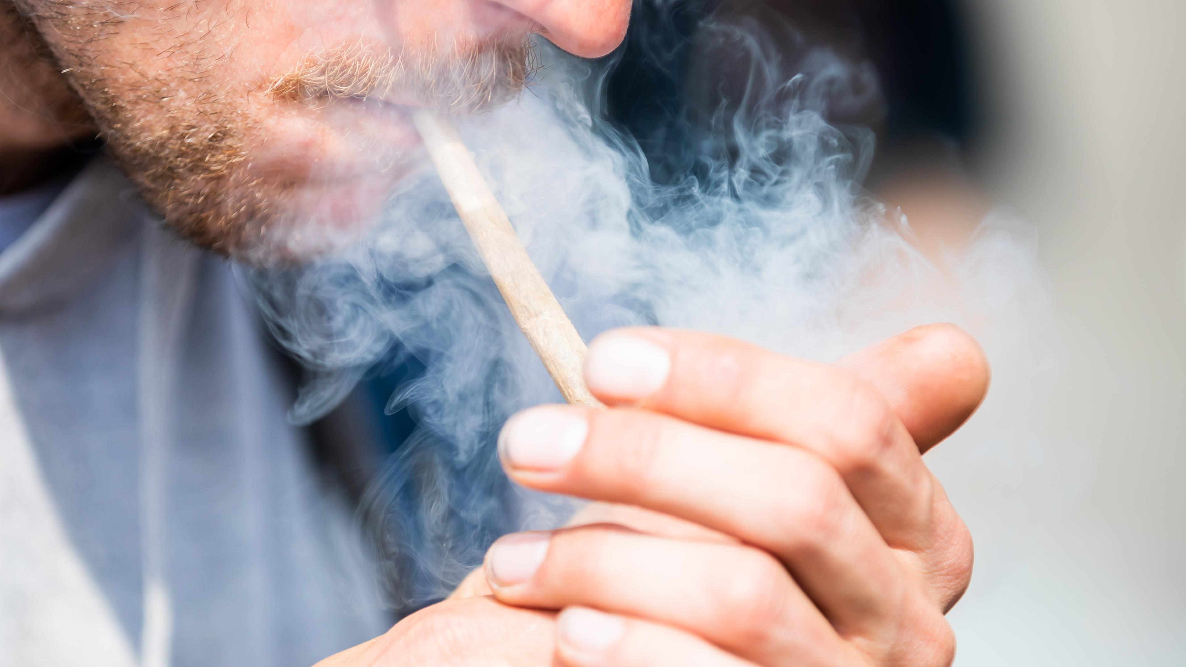 Ein Mann raucht bei der Auftaktkundgebung einer Demonstrationen für eine zügige Legalisierung von Cannabis, dem «Global Marijuana March 2022», am Brandenburger Tor einen Joint mit Medizinalcannabis