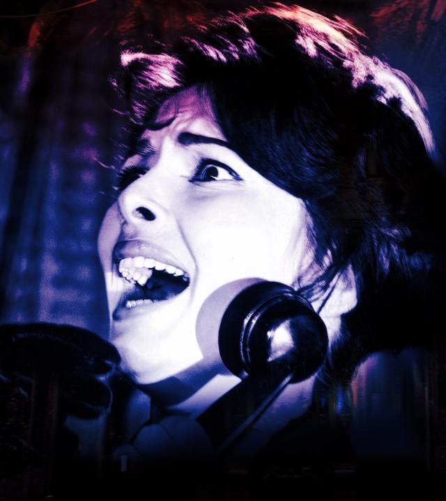 Eine verängstigte Frau mit aufgerissenen Augen hält einen Telefonhörer, während sie von einer maskierten Gestalt bedroht wird.