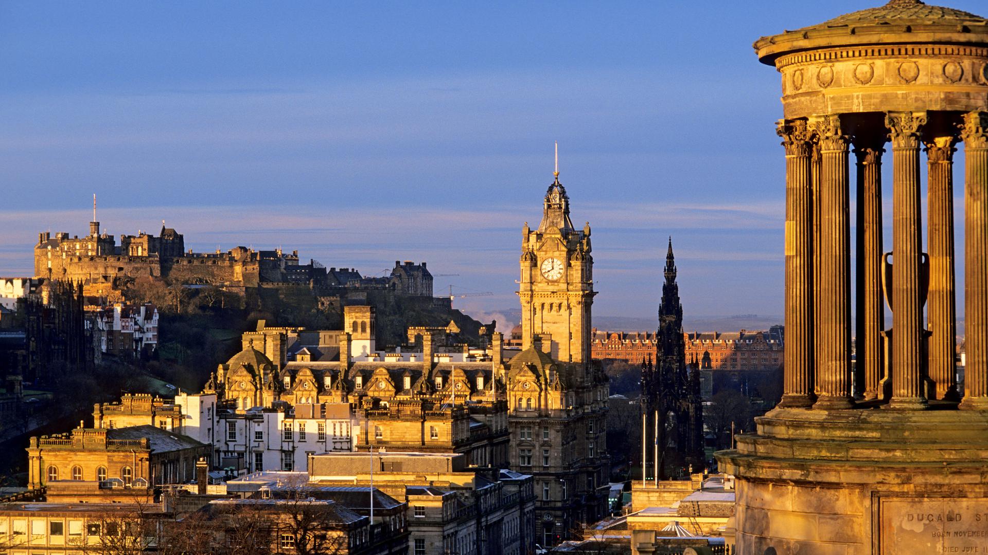 Calton Hill in goldenem Abendlicht vor tiefblauem Himmel.