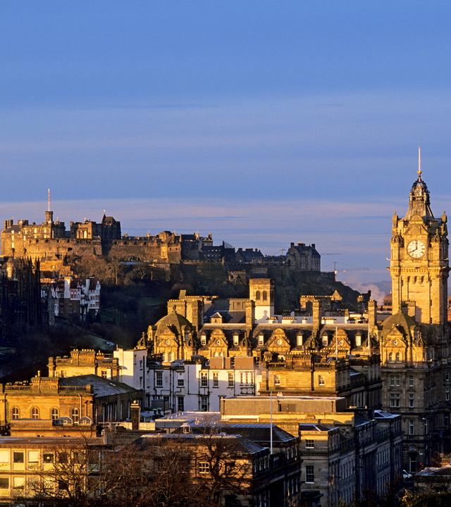 Calton Hill in goldenem Abendlicht vor tiefblauem Himmel.