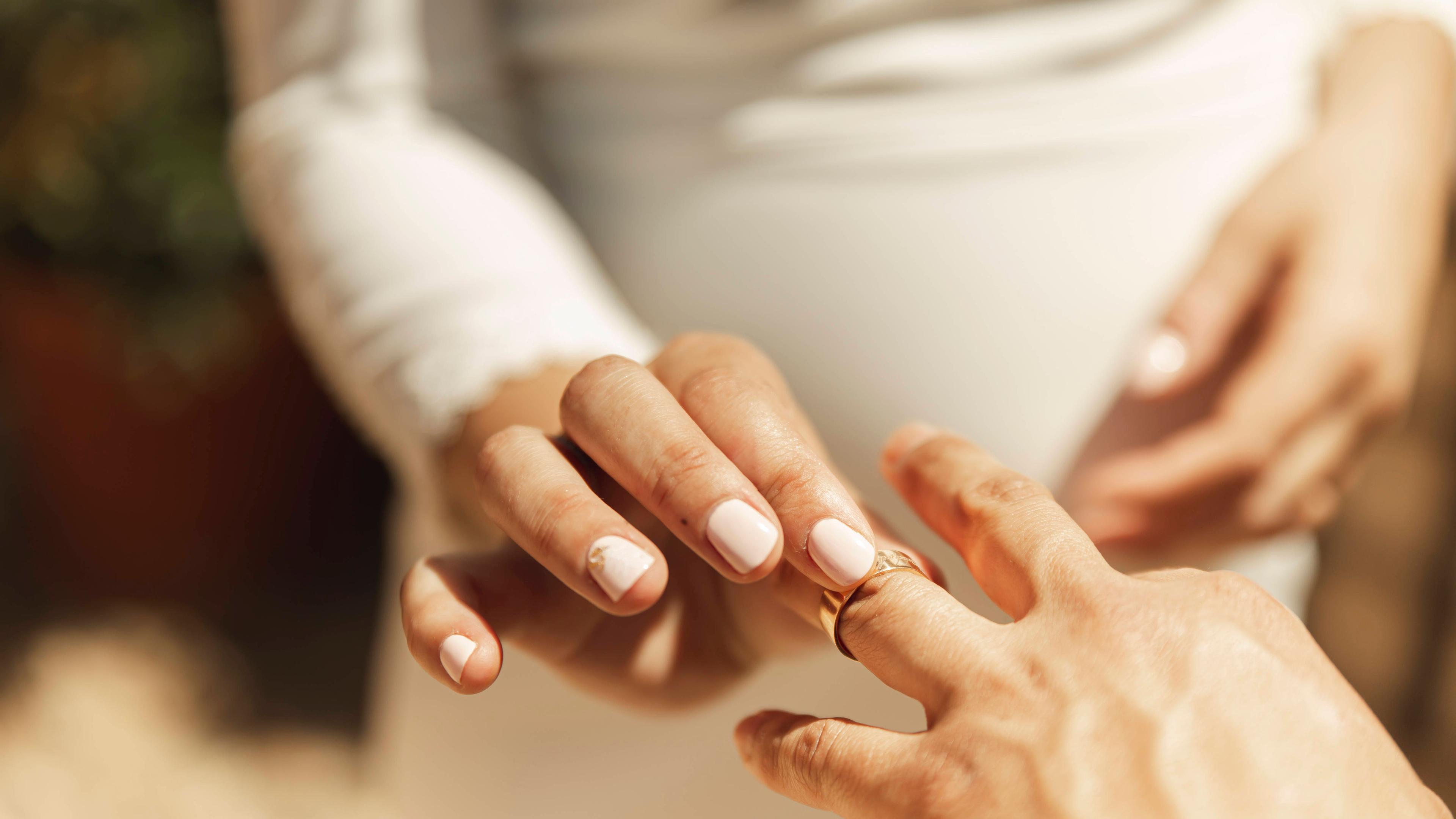 Hand der Braut legt Ehering auf den Finger des Bräutigams