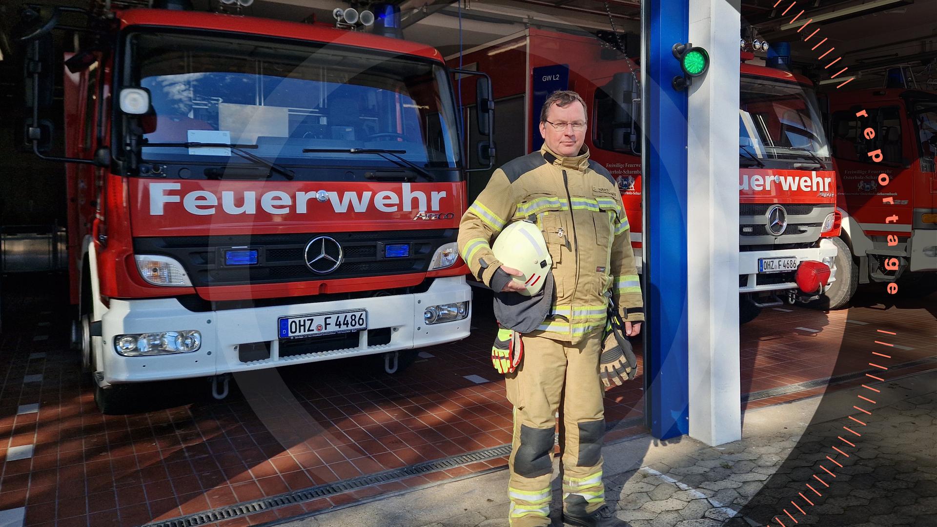Chris Hartmann steht vor einer Garage mit Einsatzfahrzeugen der Feuerwehr. Er schaut in die Kamera.