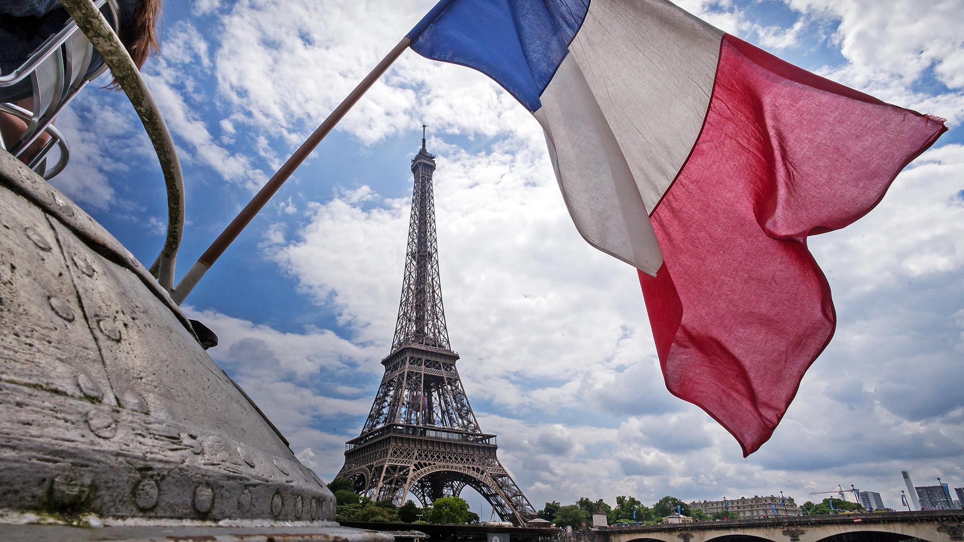 Die französische Flagge weht am heck eines Schiffes vor dem Eiffelturm in Paris (Frankreich)