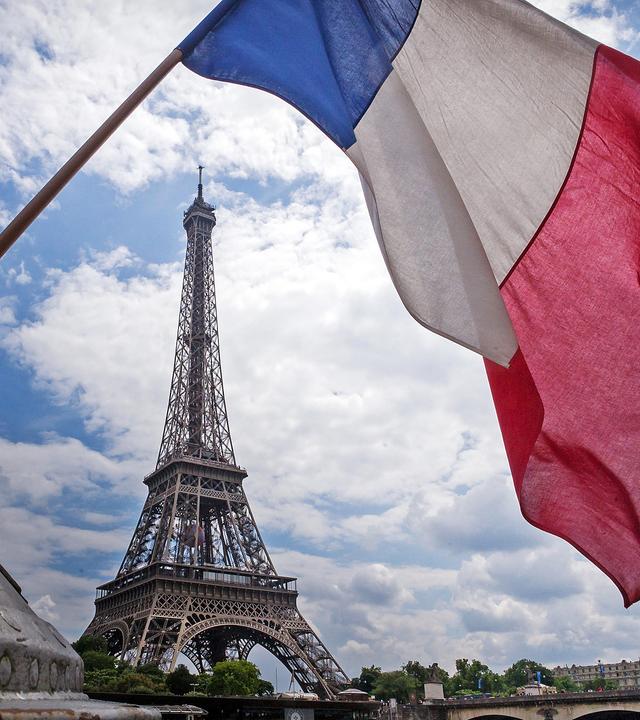 Die französische Flagge weht am heck eines Schiffes vor dem Eiffelturm in Paris (Frankreich)