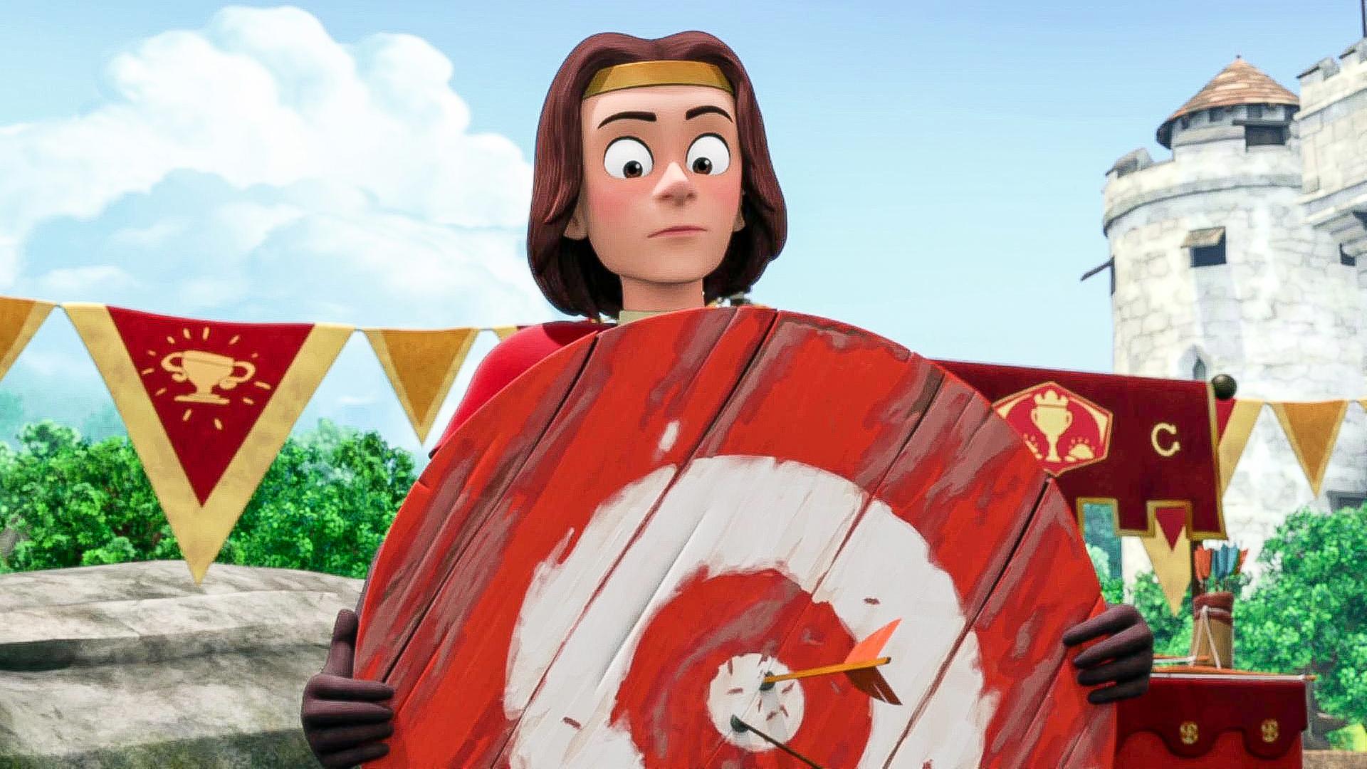 König Richard hält eine Zielscheibe aus Holz in den Händen. In der Mitte stecken zwei Pfeile. Er sieht überrascht aus.