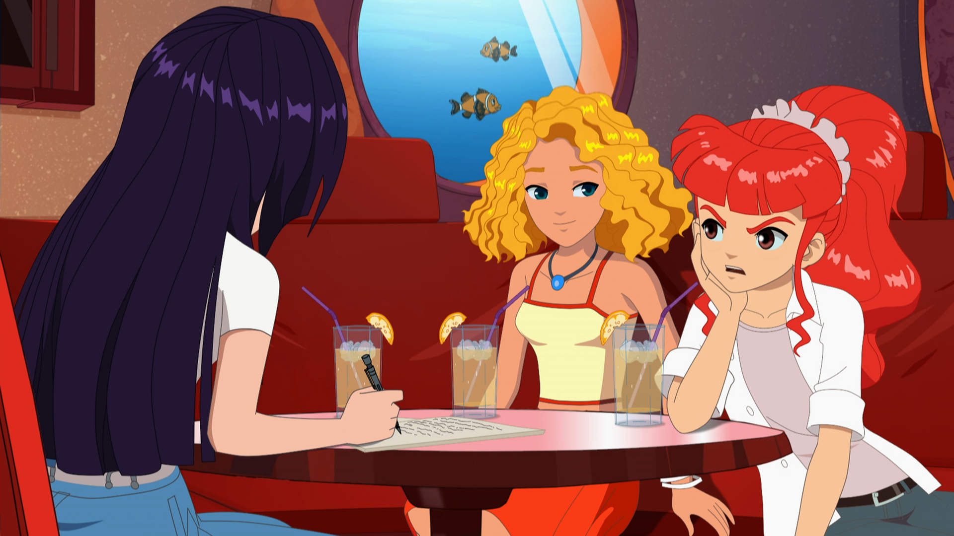 Rikki, Emma und Cleo sitzen zusammen im Café. Rikki schaut sehr verärgert.