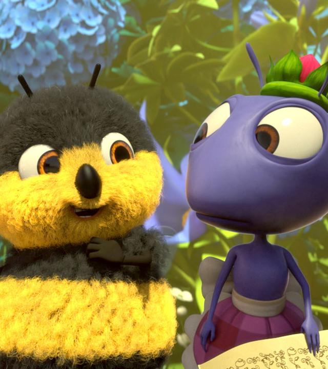 Heini Hummel (links) hält das Drehbuch in der rechten Hand. Anna Ameise steht rechts neben ihm und hält auch ein Stück Papier in der Hand. Heini wirkt erfreut, Anna geschockt.