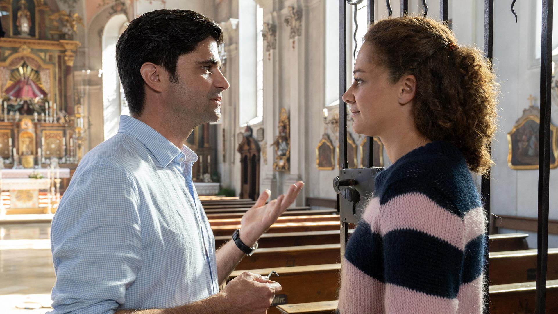 "Tonio & Julia - Ein neues Leben": In einer Kirche stehen sich Julia Schindel (Oona Devi Liebich) und Tonio Niederegger (Maximilian Grill) gegenüber und reden miteinander.