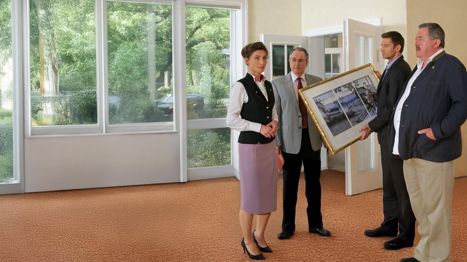 "Die Rosenheim-Cops - Ein Smoking zum Sterben": Die Kommissare Hansen (Igor Jeftic) und Hofer (Joseph Hannesschläger) unterhalten sich in einem Zimmer der Villa mit Isolde Richter (Daniela Kiefer) und Anwalt Fischbach (Norbert Heckner). Hansen hält ein großes Bild in seinen Händen und sieht Frau Richter eindringlich an. Auch die beiden anderen Männer schauen sie an.