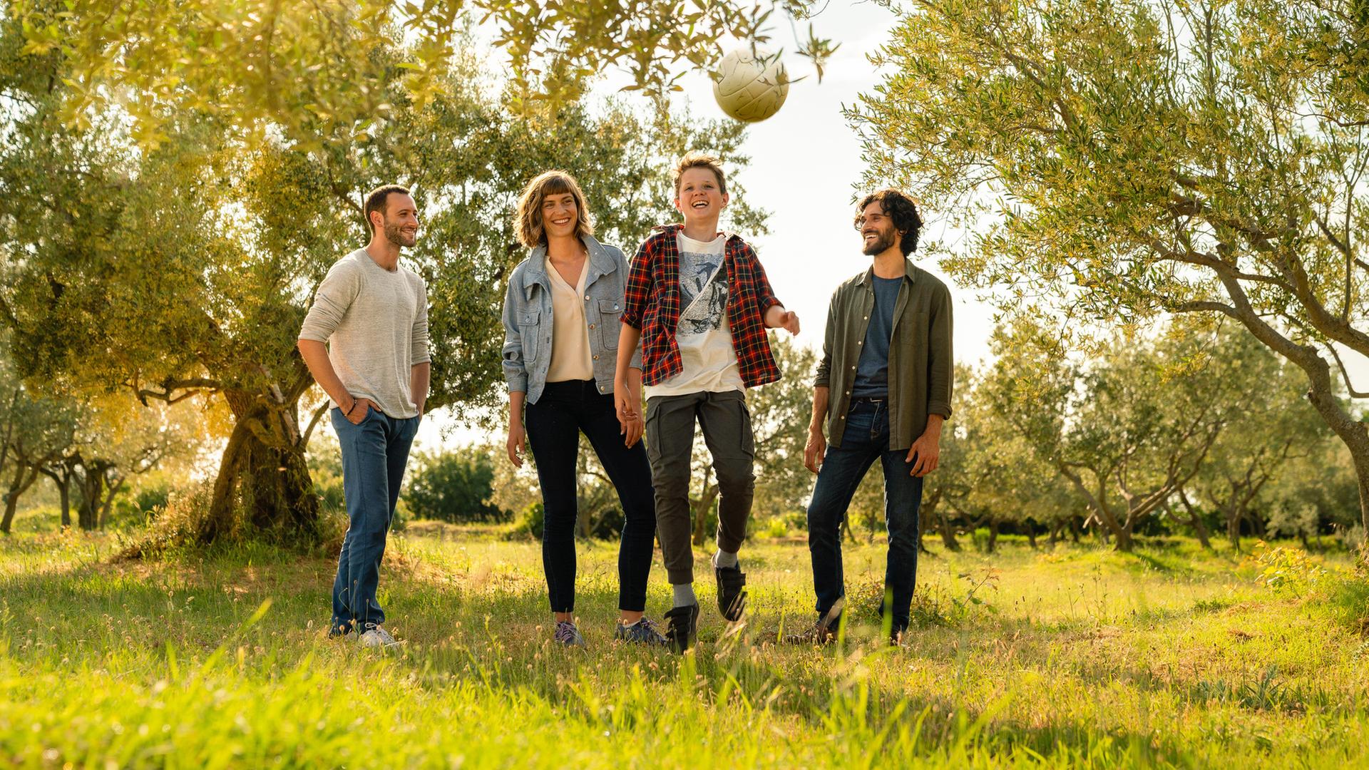 Unter Bäumen auf einer Wiese schießt Matija (Xaver Pucci) einen Fußball in die Luft. Anne Schuster (Sophie Pfennigstorf), Darijo (Vladimir Korneev) und Zoran (Tim Borys) stehen ganz dicht hinter ihm und schauen zu.