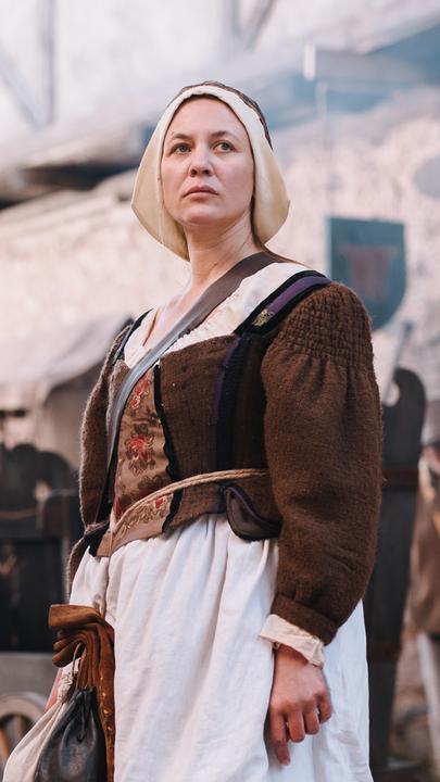 Spielszene: Hebamme Anna Stein (Julia Thurnau)  steht auf der Straße zwischen anderen Menschen