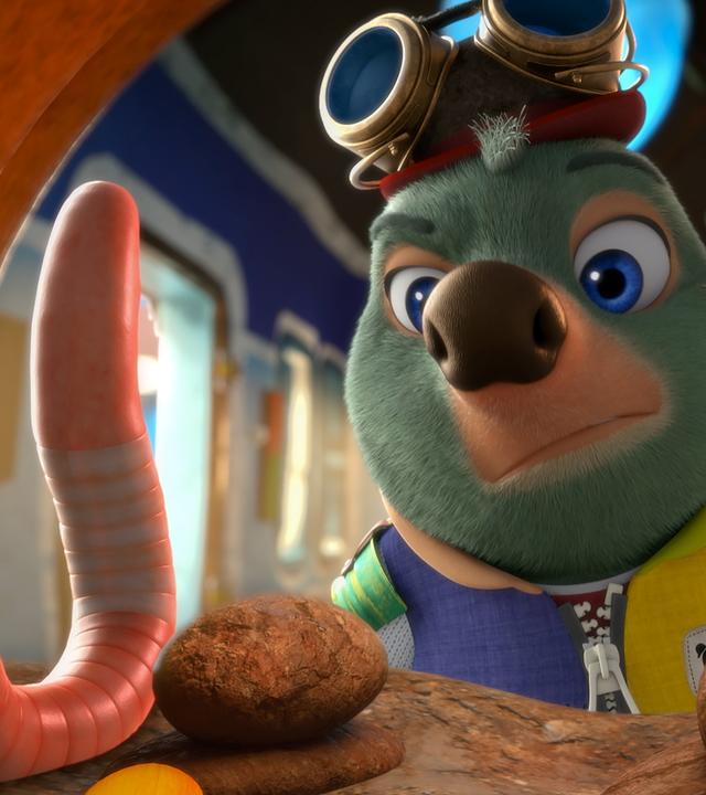 Moley steht wenig begeistert vor zwei aufgerichteten Würmern, die sich in einer Art Wurmkuschelhäuschen befinden.