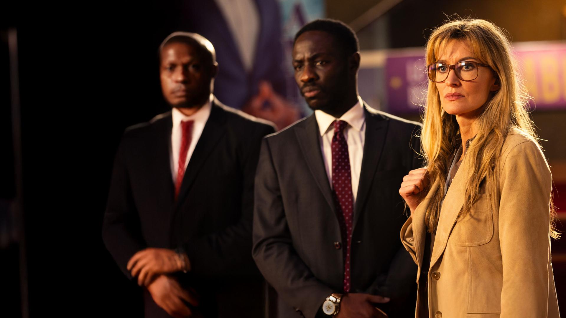 "The Kollective - Eine heiße Spur": Maya (Natascha McElhone) und Senator Lusamba (Ralph Amoussou) stehen nebeneinander in einem Gebäude. Sie beobachten etwas.