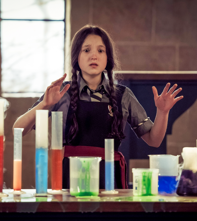 Mildred steht verzweifelt vor Gläschen mit bunten Zaubertränken.