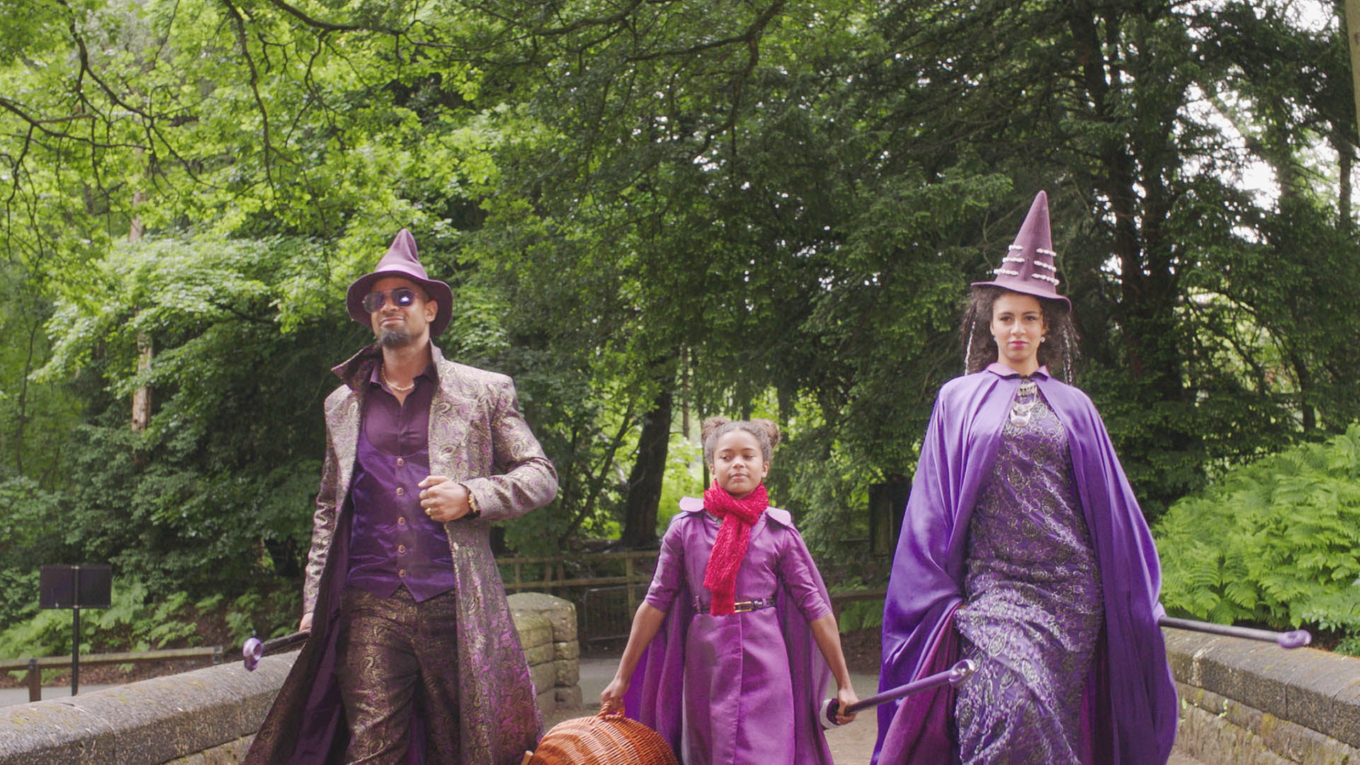 Edith, die neue Schülerin mit ihren prominenten Eltern in lilanen Hexenumhängen und Hexenhüten.