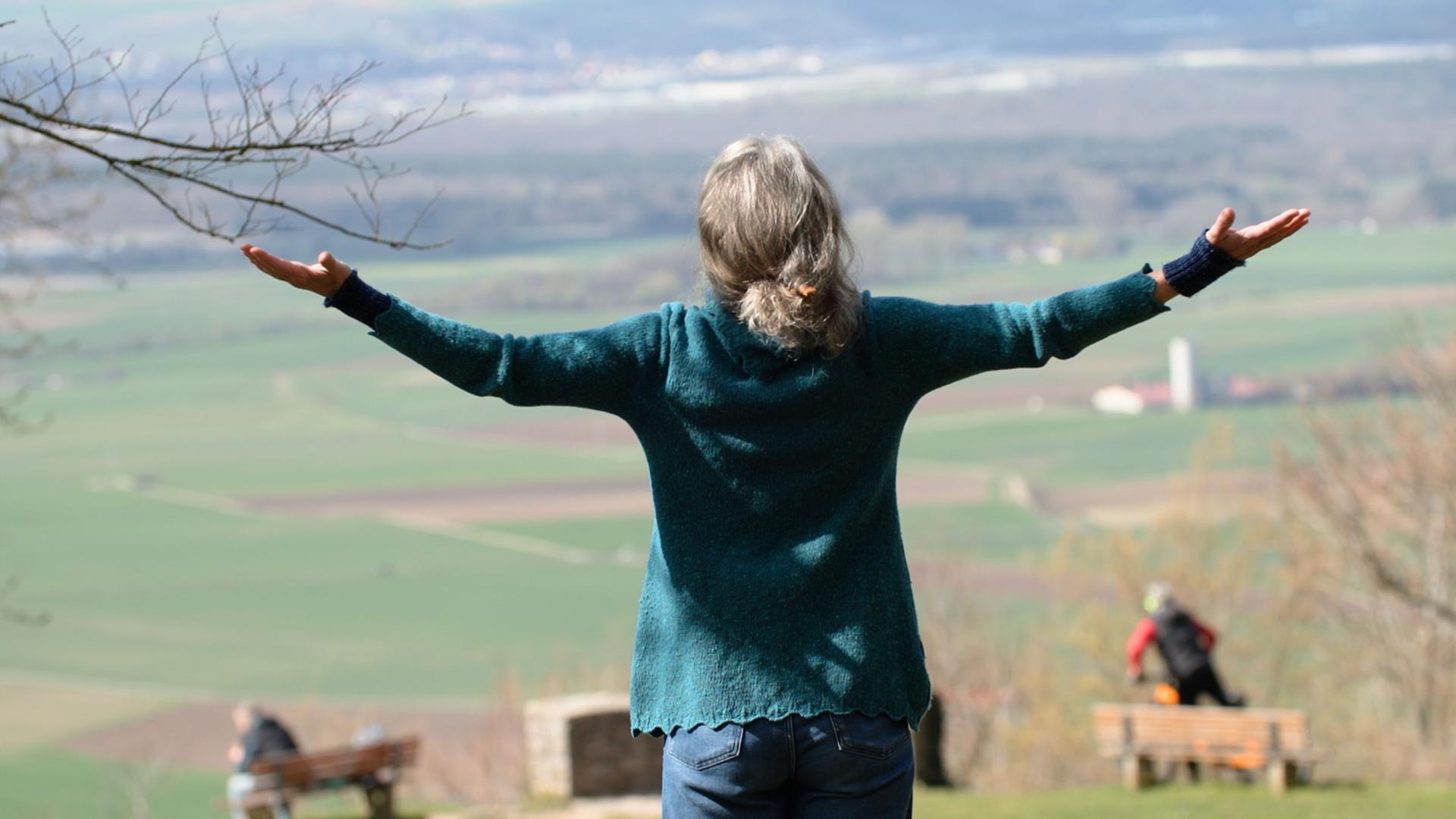 Schwester Franziska steht mit ausgebreiteten Armen auf einem Berg.