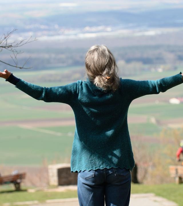Schwester Franziska steht mit ausgebreiteten Armen auf einem Berg.