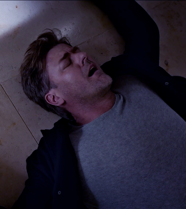 Harald Neuhauser (Marcus Mittermeier) liegt rücklings auf Steinfliesen, in der rechten Hand seine Waffe. 