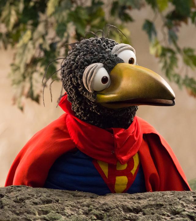 Rabe Rudi trägt seinen roten Super-Rudi-Umhang.