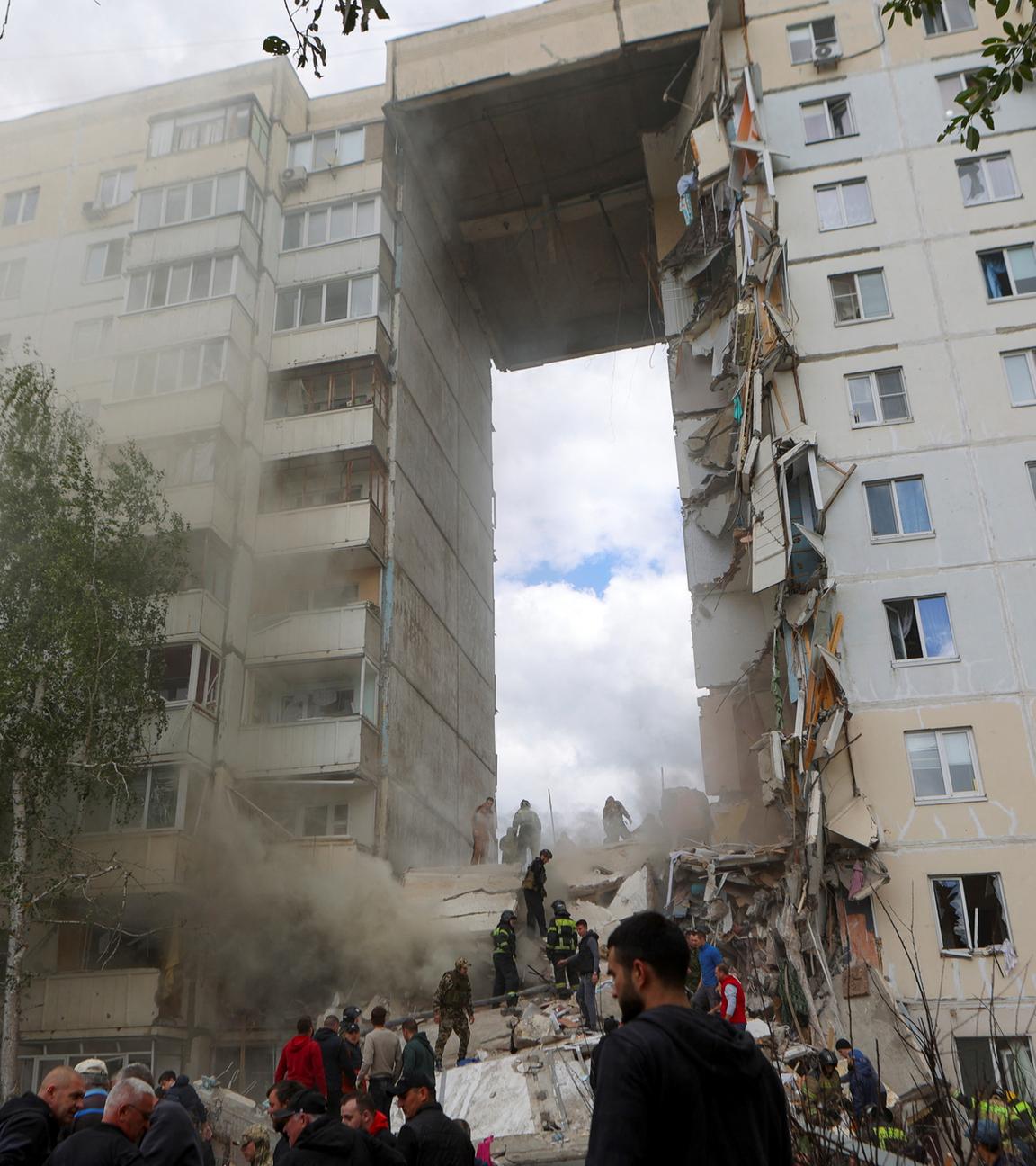 Russland, Belgorod: Menschen beseitigen Trümmer auf der Suche nach Überlebenden nach dem Einsturz eines Teils eines mehrstöckigen Wohnblocks als Folge eines ukrainischen Raketenangriffs.