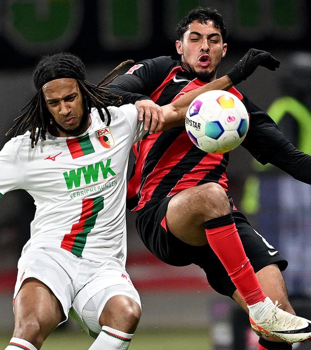 Augsburgs Kevin Mbabu (l) und Frankfurts Farès Chaibi kämpfen um den Ball.